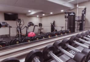 A gym with free weights in the foreground, treadmills, stationary bikes, and a cable machine in the background.